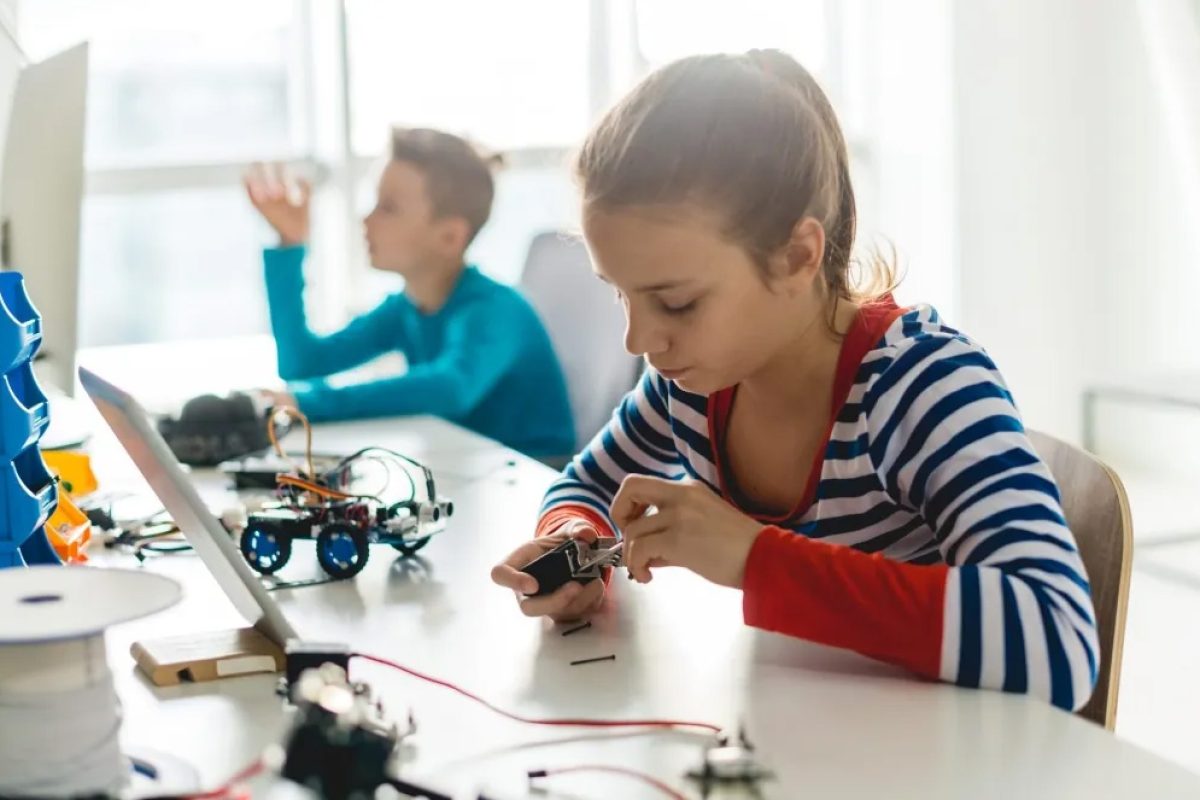 Zwei Kinder arbeiten konzentriert in einem MINT-Workshop mit Technik und elektronischen Bauteilen.