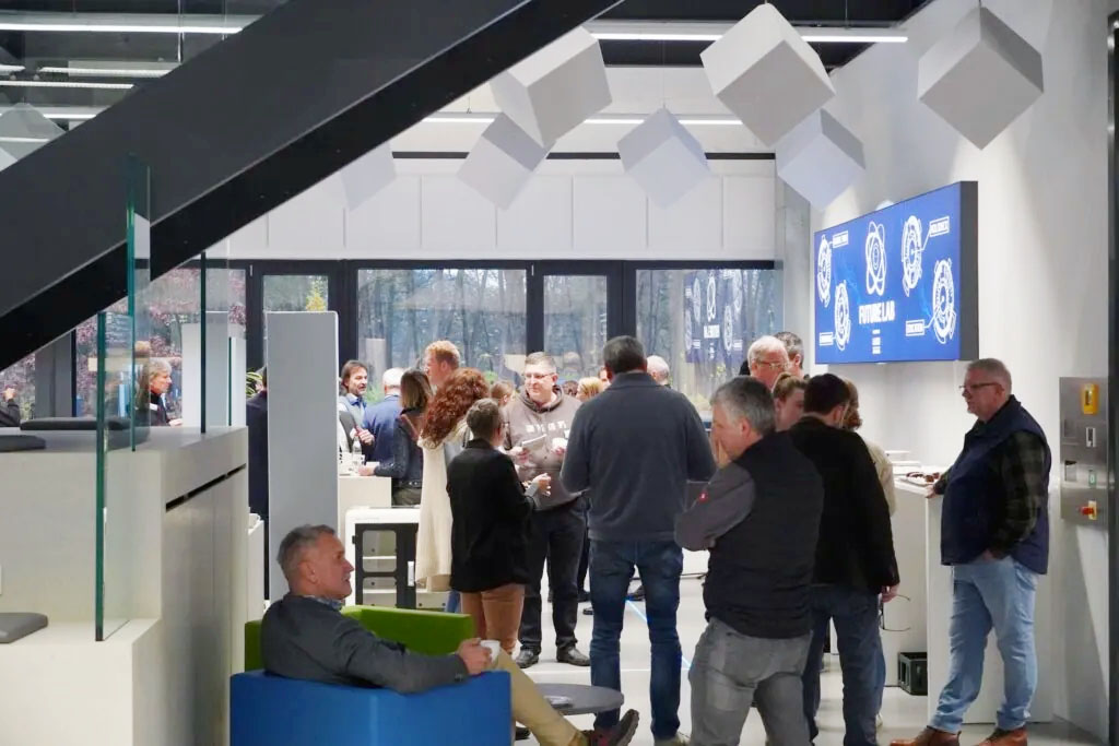 Menschen tauschen sich bei einem MINT-Netzwerktreffen in modernem Raum mit Bildschirmen aus.