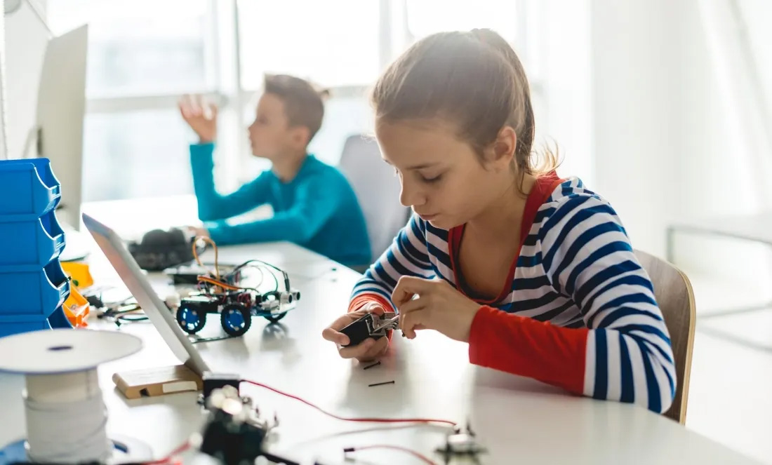 Zwei Kinder arbeiten konzentriert in einem MINT-Workshop mit Technik und elektronischen Bauteilen.