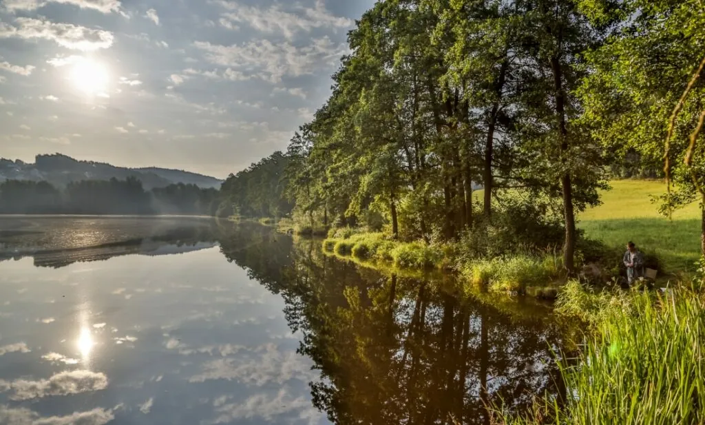 Morgendliche Teichlandschaft mit Angler, Spiegelungen im Wasser und friedlicher Natur in der Oberpfalz.
